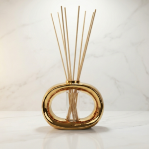 Gold reed diffuser with natural reeds on marble surface, luxury home décor