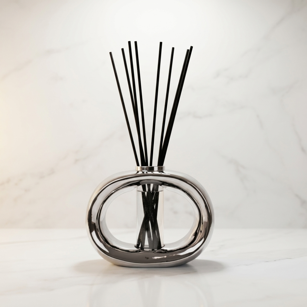 Chrome silver reed diffuser with black sticks on marble surface, modern home fragrance